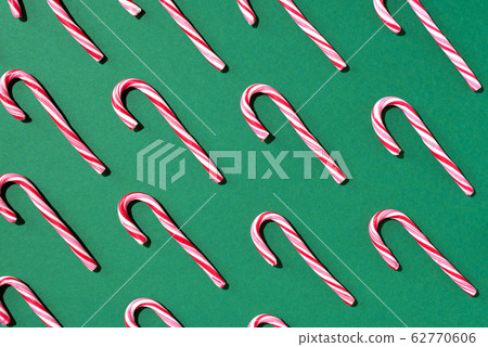 Pattern of Christmas candy cane on green background. Top view. Flat lay. Creative minimal concept. Greeting card on Christmas and New Year. Art composition. Pattern of Christmas candy cane on green background. Top view. Flat lay. Creative minimal concept. Greeting card on Christmas and New Year. Art composition. 62770606