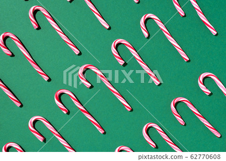 Pattern of Christmas candy cane on green background. Top view. Flat lay. Creative minimal concept. Greeting card on Christmas and New Year. Art composition. Pattern of Christmas candy cane on green background. Top view. Flat lay. Creative minimal concept. Greeting card on Christmas and New Year. Art composition. 62770608