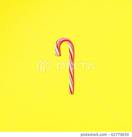 Christmas candy cane on yellow background with copy space. Top view. Greeting card on Christmas and New Year. Minimal festive concept 62770630