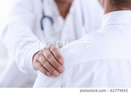 Friendly male doctor hold patient shoulder in office during reception 62774842