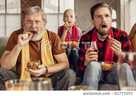 Excited, happy big family team watch football, soccer match together on the couch at home 62775055