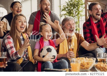 Excited, happy big family team watch football, soccer match together on the couch at home 62775121
