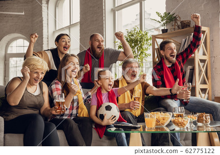 Excited, happy big family team watch football, soccer match together on the couch at home 62775122