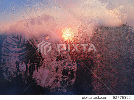 Ice patterns, water drops and sunlight on a window Ice patterns, water drops and sunlight on a window 62776593