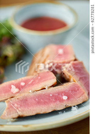 Closeup Medium rare tuna with lettuce and hot sauce. Restaurant menu Closeup Medium rare tuna with lettuce and hot sauce. Restaurant menu 62778281