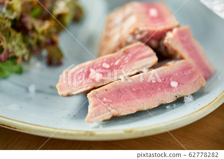 Closeup Medium rare tuna with lettuce and hot sauce. Restaurant menu 62778282