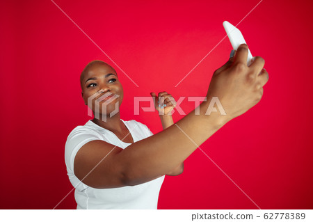 African-american young woman's portrait on red background 62778389