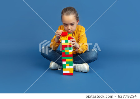 Portrait of sad little girl sitting on blue studio background, autism concept 62779254