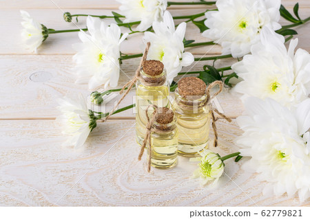 Chrysanthemum essential oil in small glass bottles and white chrysanthemum flowers 62779821