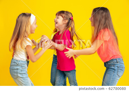 Happy children playing and having fun together on yellow studio background Happy children playing and having fun together on yellow studio background 62780080
