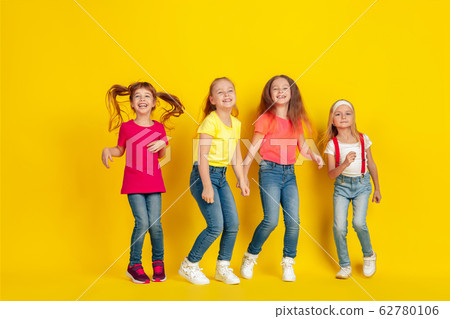 Happy children playing and having fun together on yellow studio background Happy children playing and having fun together on yellow studio background 62780106