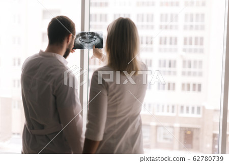 Two confident doctor discuss X-ray of patient in meeting room Two confident doctor discuss X-ray of patient in meeting room 62780739