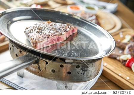 Grilled striploin steak. The strip steak or New York strip On a metal plate with coal. Barbecue restaurant menu. 62780788