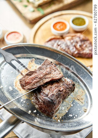 The waiter is butchering griled meat with a knife. Grilled fillet steaks with Pickled cabbage and two sauces.. Barbecue restaurant menu. The waiter is butchering griled meat with a knife. Grilled fillet steaks with Pickled cabbage and two sauces.. Barbecue restaurant menu. 62780799