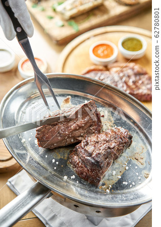 Grilled fillet steaks. A piece of meat cut in two. Barbecue restaurant menu. On a metal plate with coal. Chateaubriand Steak Grilled fillet steaks. A piece of meat cut in two. Barbecue restaurant menu. On a metal plate with coal. Chateaubriand Steak 62780801