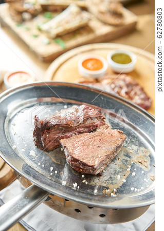 Grilled fillet steaks. A piece of meat cut in two. Barbecue restaurant menu. On a metal plate with coal. Chateaubriand Steak 62780803