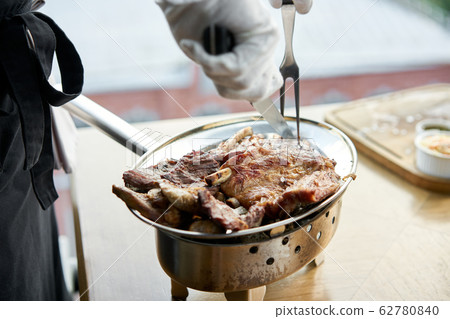 The waiter is butchering with a knife. Various grilled meat set. Barbecue restaurant menu, a series of photos of different meats. 62780840