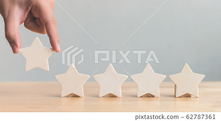 Hand putting wooden five star shape on table. The best excellent business rating customer experience 62787361