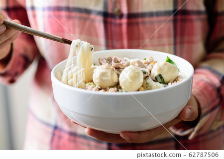 Rice noodles soup with pork and meat ball in a bowl eating by chopsticks 62787506