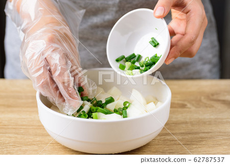 Kimchi radish cooking, step 2; mixing sliced spring onion and radish in a bowl Kimchi radish cooking, step 2; mixing sliced spring onion and radish in a bowl 62787537