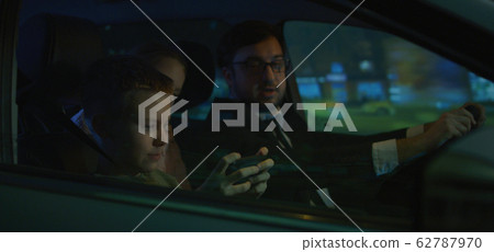 Man driving and son playing on phone 62787970