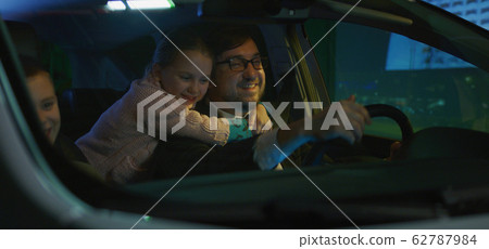 Father driving his children home at night 62787984