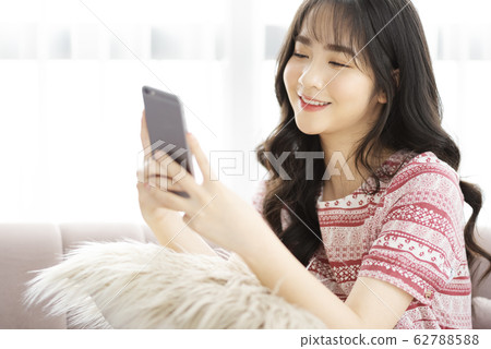 A young lady with a smartphone on the sofa 62788588