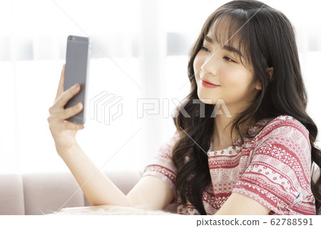 A young lady with a smartphone on the sofa 62788591