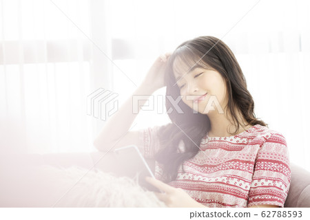 A young lady with a smartphone on the sofa 62788593