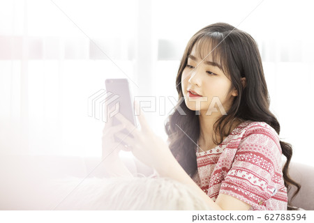 A young lady with a smartphone on the sofa 62788594