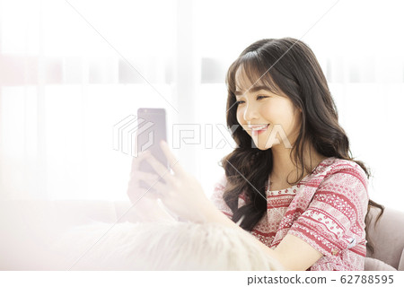 A young lady with a smartphone on the sofa 62788595