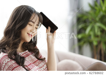 A young lady with a smartphone on the sofa 62788602