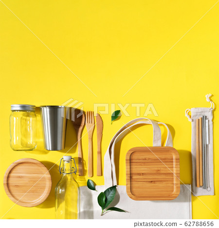 Sustainable lifestyle. Zero waste, plastic free shopping concept. Cotton bags, glass jar, bottle, metal cup, straws for drinking, bamboo cutlery and boxes on yellow background. Sustainable lifestyle. Zero waste, plastic free shopping concept. Cotton bags, glass jar, bottle, metal cup, straws for drinking, bamboo cutlery and boxes on yellow background. 62788656