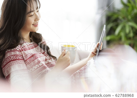 A young lady with a smartphone on the sofa 62788968