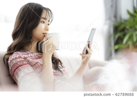 A young lady with a smartphone on the sofa A young lady with a smartphone on the sofa 62789088