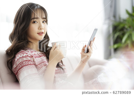 A young lady with a smartphone on the sofa A young lady with a smartphone on the sofa 62789089
