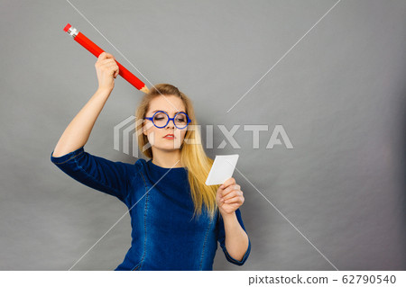 Confused woman holds big pencil note paper in hand Confused woman holds big pencil note paper in hand 62790540