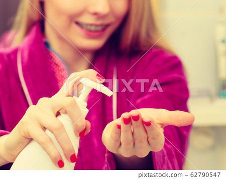 Woman applying hand cream on hands Woman applying hand cream on hands 62790547