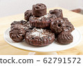 Delicious chocolate dietary candies and cookies for vegans made from natural ingredients. Tasty treats, sprinkled with coconut, on a white tray on wooden table. Healthy meal. Sweet and harmless. 62791572