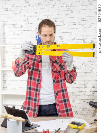 young man viewing a spirit level 62794689