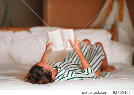 Beautiful woman reading book in bed relaxing 62795365