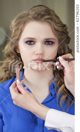 Applying makeup. The model's lips are painted with 62796203