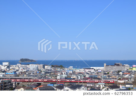 View of Keikyu's red train from the hill overlooking Uraga Suido and Sarushima Island 62796353