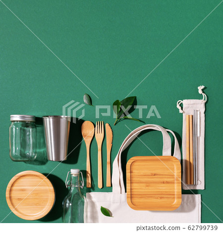 Sustainable lifestyle. Zero waste, plastic free shopping concept. Cotton bags, glass jar, bottle, metal cup, straws for drinking, bamboo cutlery and boxes on green background. Sustainable lifestyle. Zero waste, plastic free shopping concept. Cotton bags, glass jar, bottle, metal cup, straws for drinking, bamboo cutlery and boxes on green background. 62799739