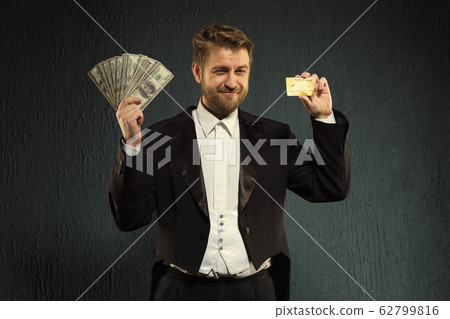 Positive man in a tailcoat offers a credit card 62799816