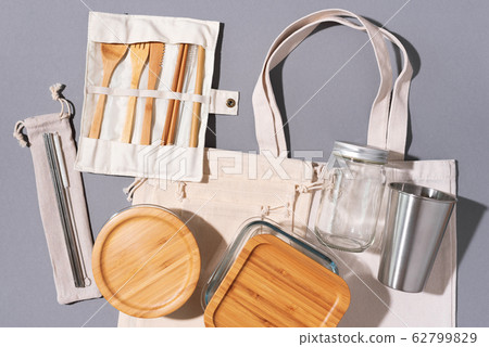 Cotton bags, glass jar, bottle, metal cup, straws for drinking, bamboo cutlery and boxes on gray background. Sustainable lifestyle. Zero waste, plastic free shopping concept. 62799829