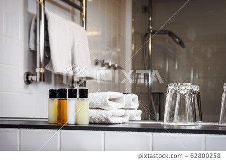 Mini bottles of cosmetics and towels on the table 62800258