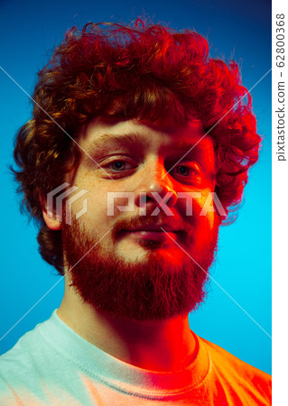 Caucasian close up man's portrait isolated on blue studio background in neon light Caucasian close up man's portrait isolated on blue studio background in neon light 62800368