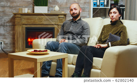 Nervous young couple sitting on couch Nervous young couple sitting on couch 62802140