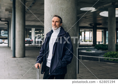 Stylish senior man standing outdoors at airport terminal looking away 62805194